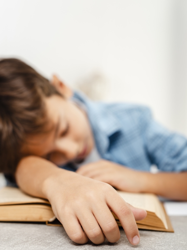 Erschöpftes Kind Erschöpftes Schulkind legt den Kopf auf sein Heft
