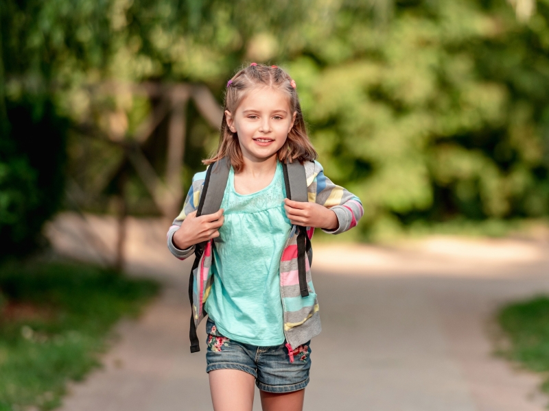 Mädchen geht entspannt mit Schulranzen zur Schule