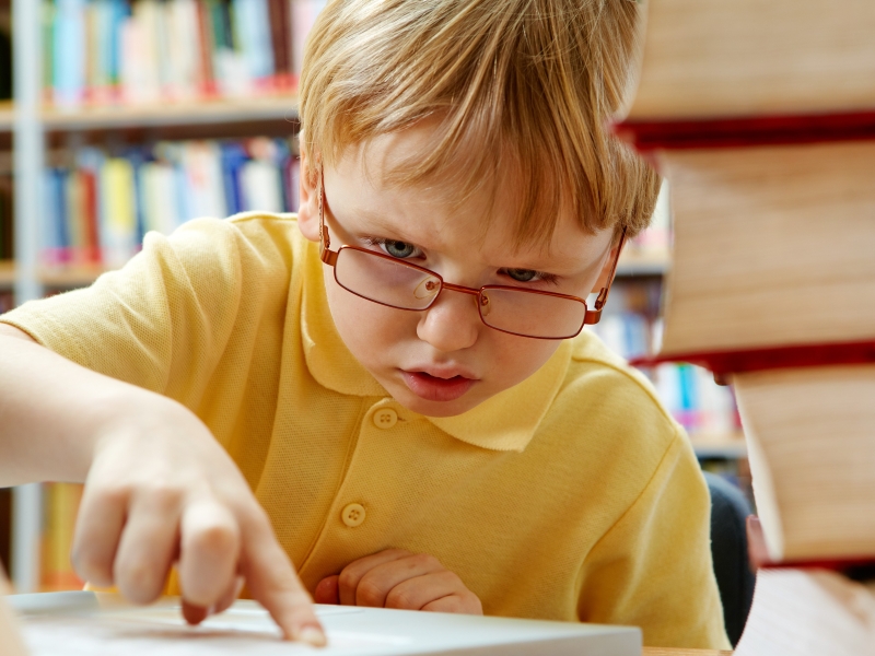 Junge mit Brille tut sich schwer beim Lesen