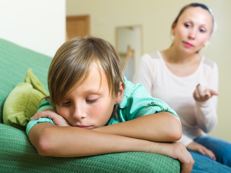 Junge zieht sich zurück, während die Mutter mit ihm spricht