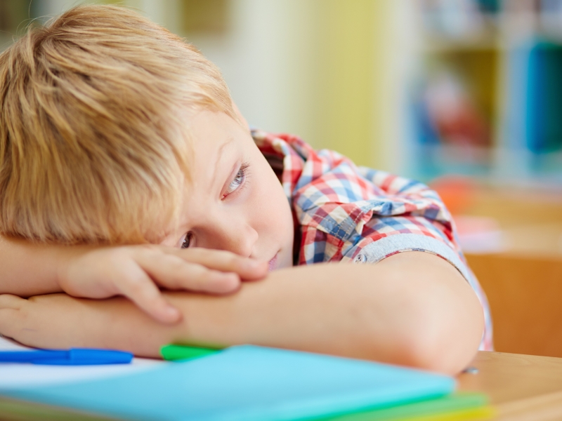 Schulkind liegt müde und unkonzentriert auf dem Tisch